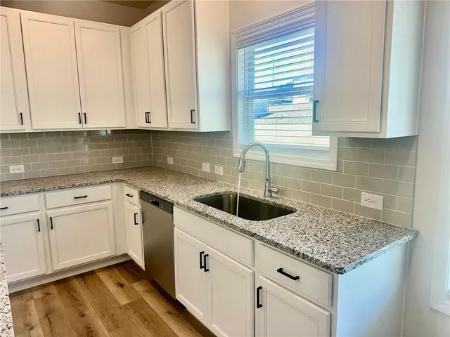 a kitchen with stainless steel appliances granite countertop white cabinets and a sink