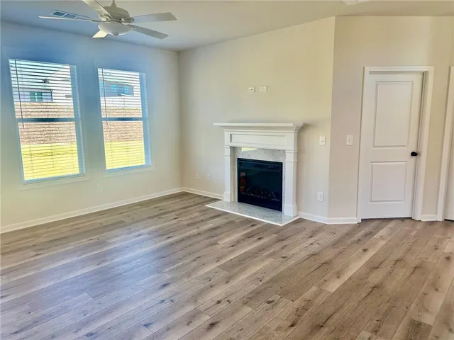 an empty room with wooden floor fireplace and windows