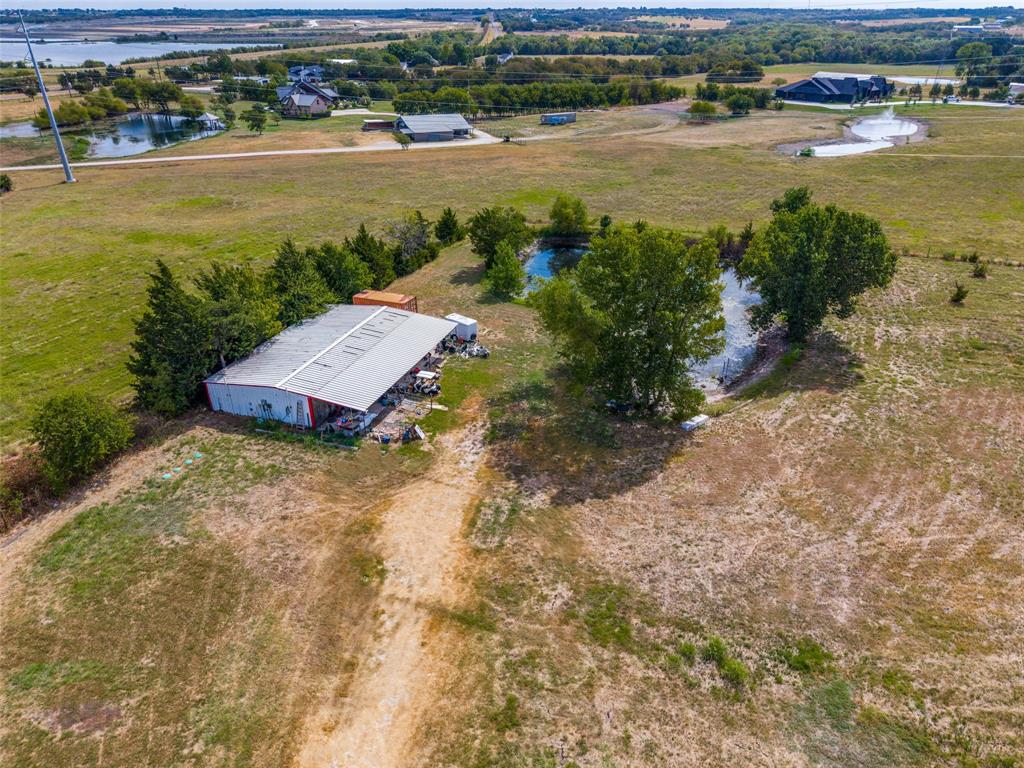 Expansive land parcel featuring multiple ponds, a large outbuilding with a metal roof, and abundant mature trees