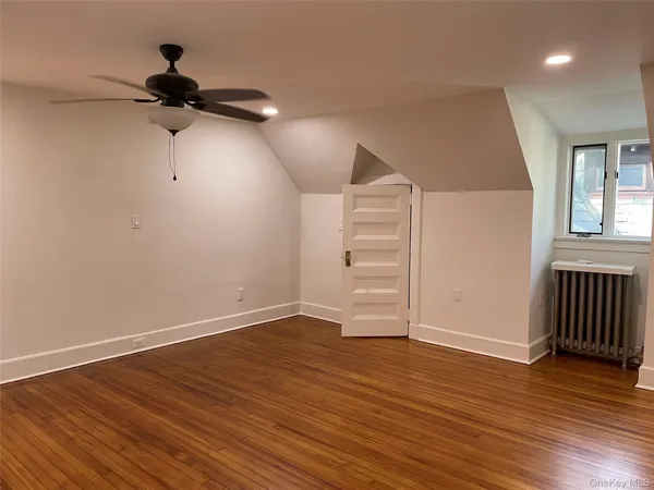 an empty room with wooden floor chandelier fan and windows