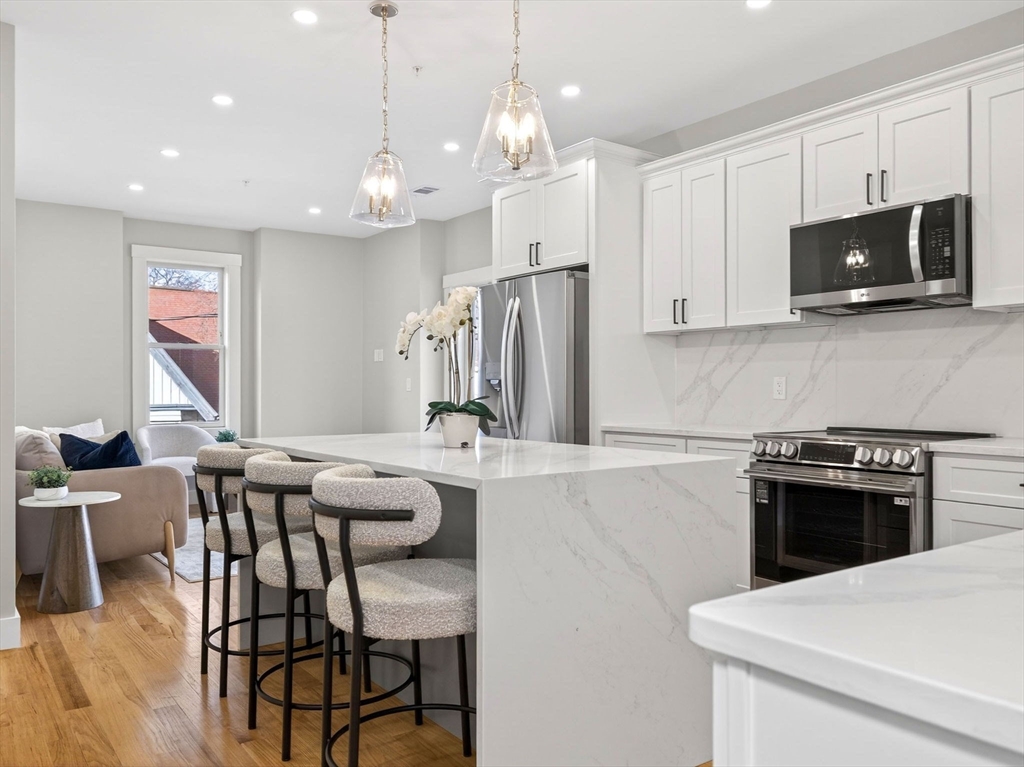 60 Stanley Street, Unit 203 Boston, MA 02125 - Photo 5 of 22 a kitchen with stainless steel appliances granite countertop a stove a sink a microwave a refrigerator and a stove