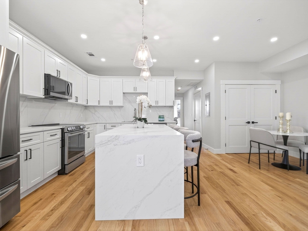 60 Stanley Street, Unit 203 Boston, MA 02125 - Photo 8 of 22 a kitchen with kitchen island a stove a sink a oven a dining table and chairs