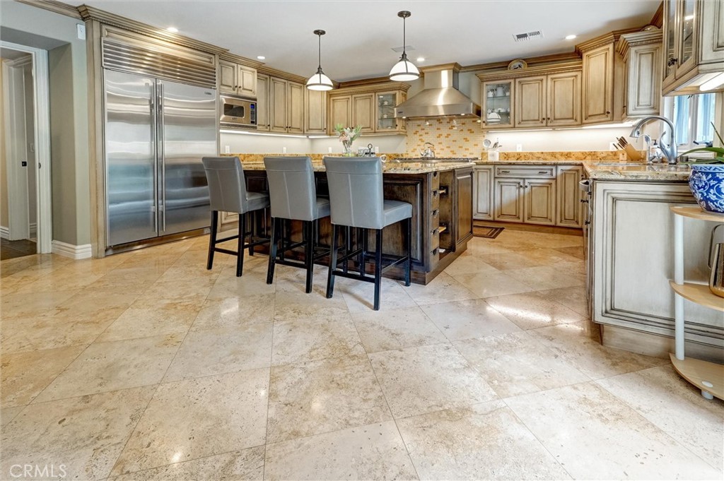 4751 Topeka Drive Tarzana, CA 91356 - Photo 15 of 65 a kitchen with kitchen island granite countertop a table chairs sink and cabinets