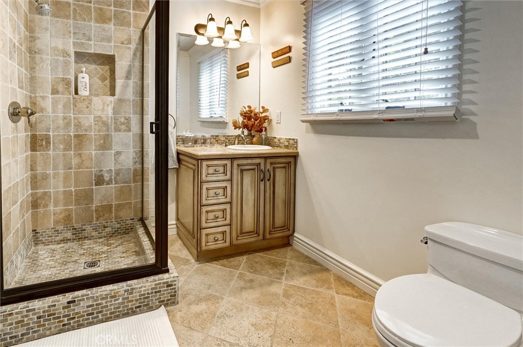 4751 Topeka Drive Tarzana, CA 91356 - Photo 56 of 65 a bathroom with a granite countertop sink a toilet a mirror and shower