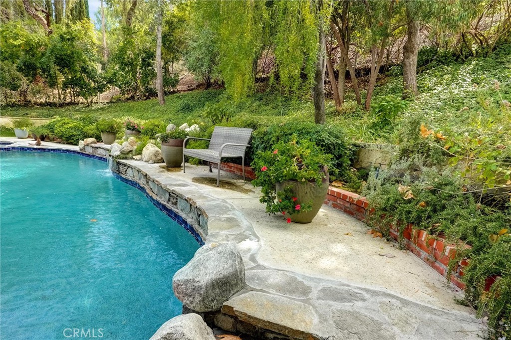 4751 Topeka Drive Tarzana, CA 91356 - Photo 61 of 65 a view of a swimming pool with lawn chairs plants and large trees