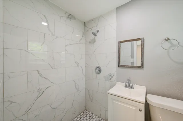 a bathroom with a toilet a sink a shower and mirror