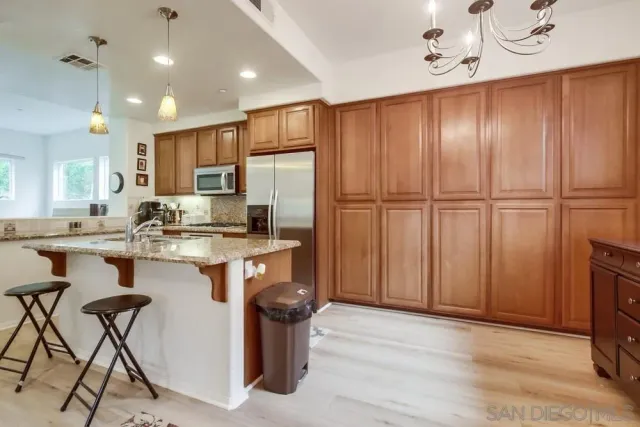 a kitchen with kitchen island granite countertop wooden cabinets and refrigerator