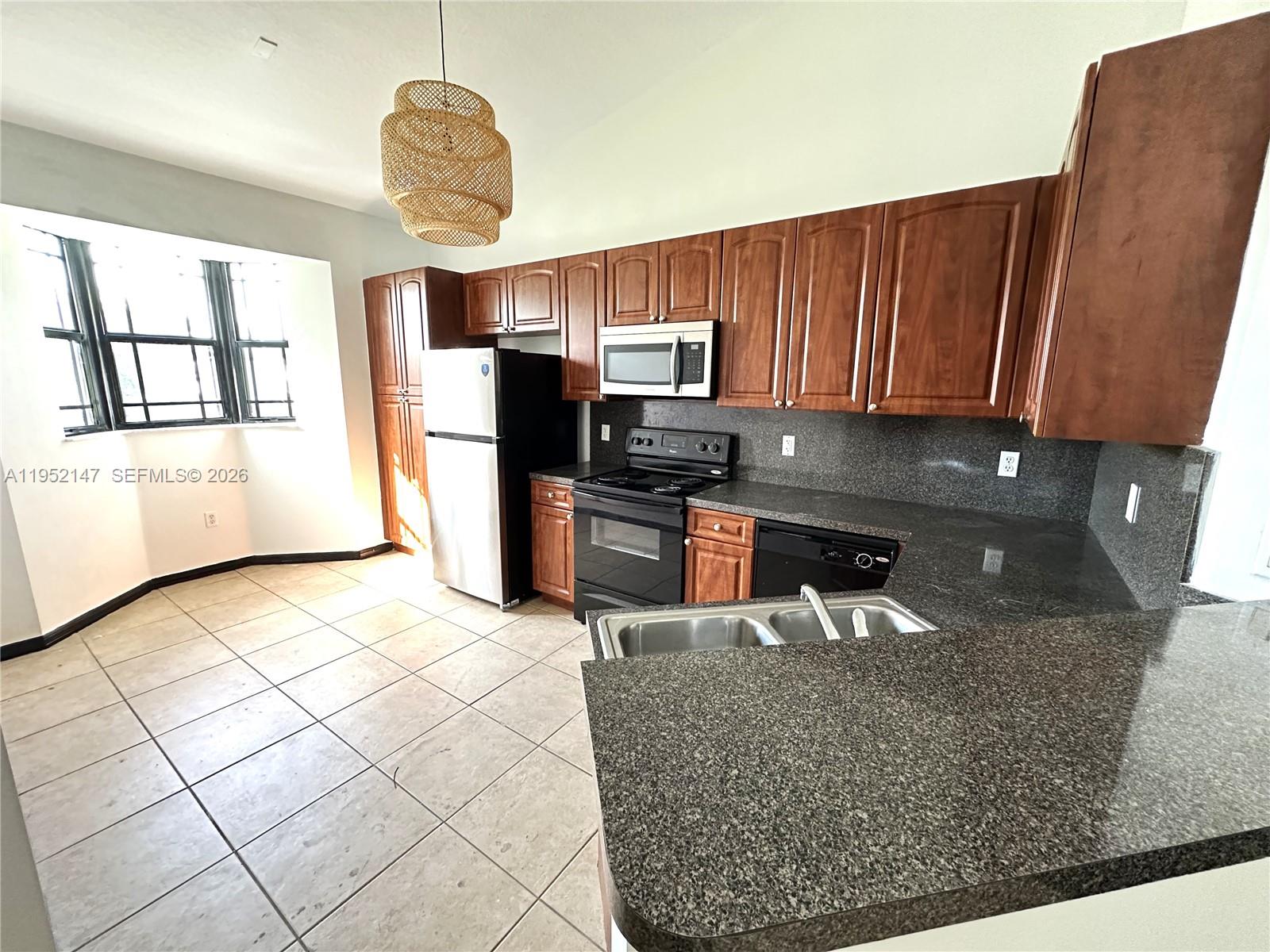 3550 Northeast 5th Street, Unit 202 Homestead, FL 33033 - Photo 11 of 23 a kitchen with stainless steel appliances granite countertop a sink refrigerator stove and microwave