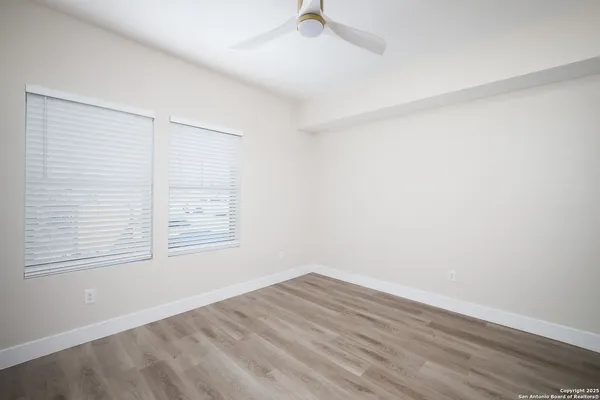 an empty room with wooden floor and windows