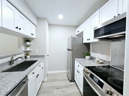 a kitchen with stainless steel appliances granite countertop a sink stove and refrigerator