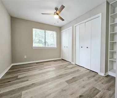 a view of empty room with wooden floor and fan
