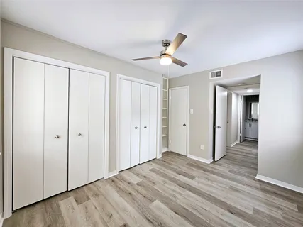 a view of empty room with wooden floor and ceiling fan