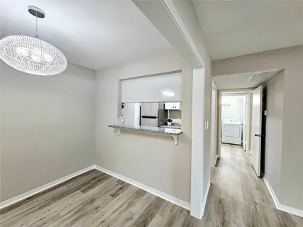 a view of a hallway with wooden floor and a living room