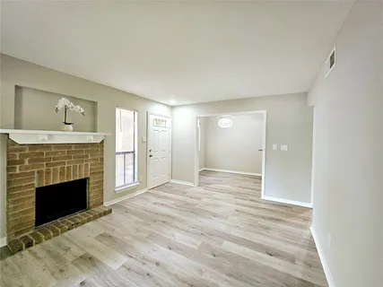 a view of an empty room with wooden floor fireplace and a window