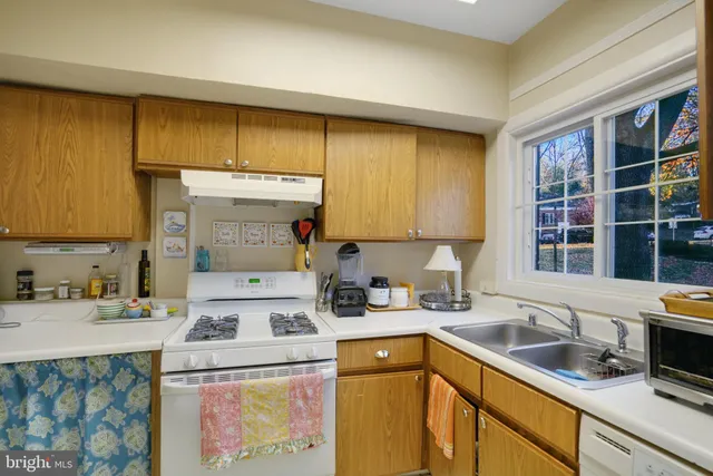 a kitchen with a sink a stove cabinets and a window