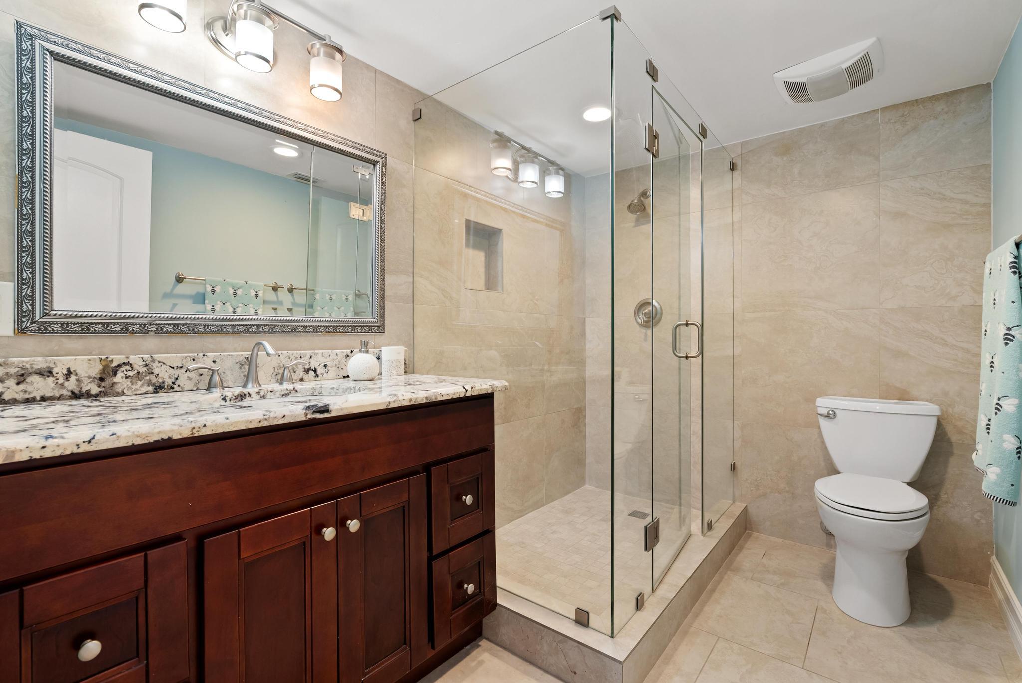 1280 Northwest 20th Avenue, Unit 101 Delray Beach, FL 33445 - Photo 20 of 31 a bathroom with a double vanity sink toilet mirror and shower