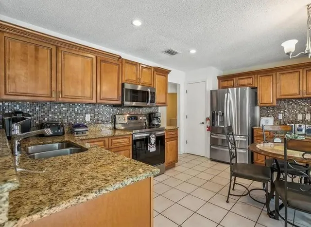 a kitchen with stainless steel appliances granite countertop a refrigerator stove top oven and sink