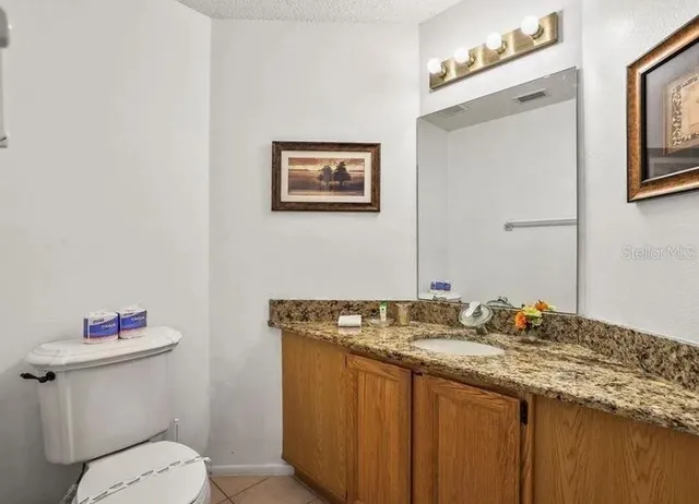 a bathroom with a granite countertop sink a toilet and a mirror