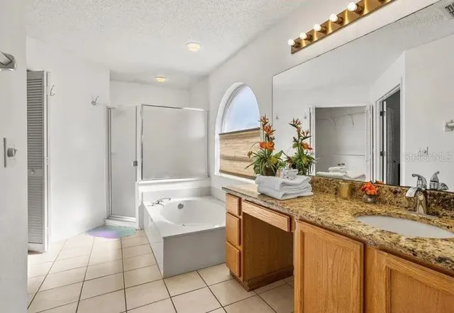 a bathroom with a granite countertop sink a mirror and a bathtub