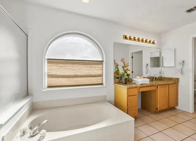 a spacious bathroom with a tub a sink and mirror