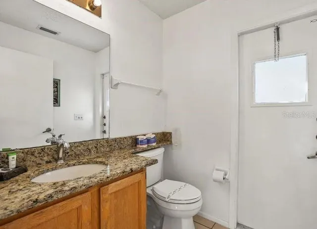 a bathroom with a granite countertop sink a toilet and a mirror