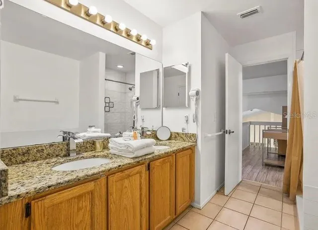 a bathroom with a granite countertop sink mirror and a shower
