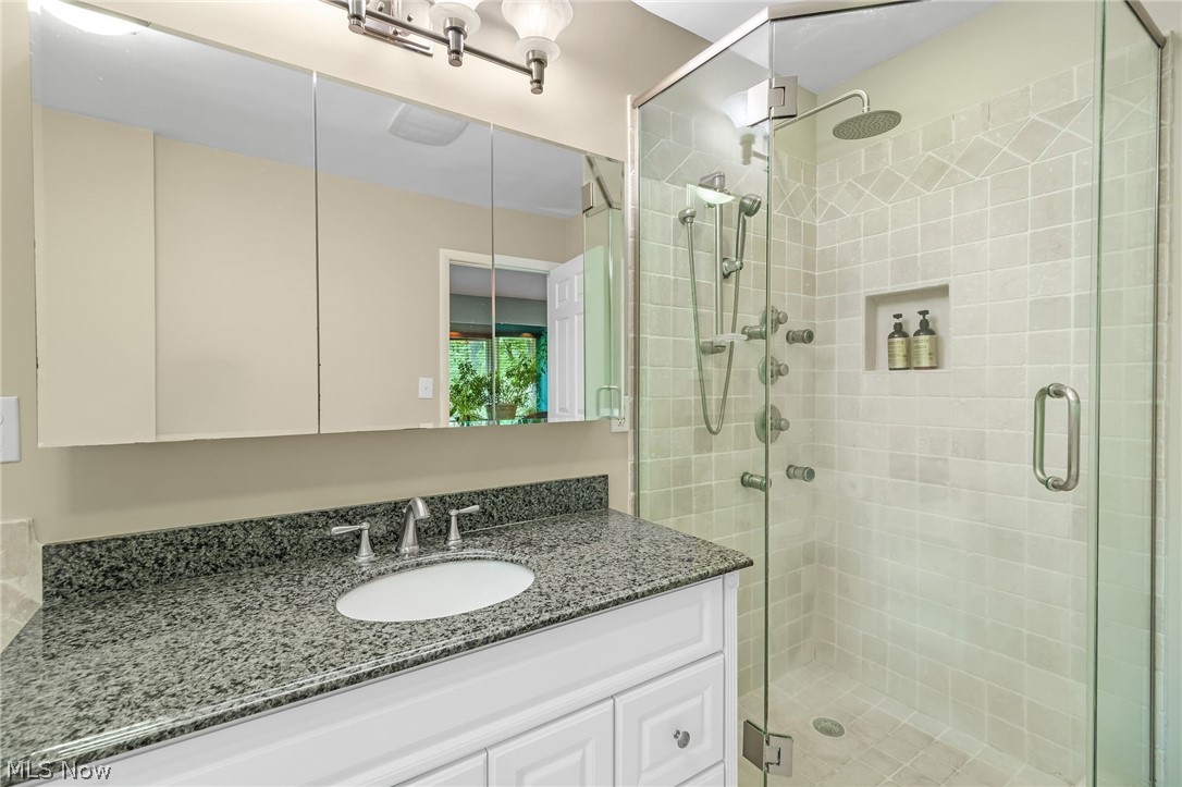 4587 Ranchwood Road Akron, OH 44333 - Photo 20 of 44 Primary Bath features white vanity with granite counter and a step-in shower.