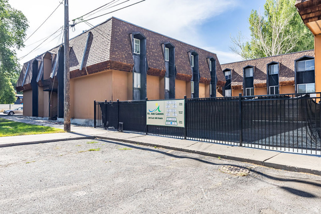 240 East 400 North, Unit 26 Logan, UT 84321 - Photo 10 of 12 Multi-story building featuring a mansard roofline with dormer windows, stucco exterior, and a dark metal fence