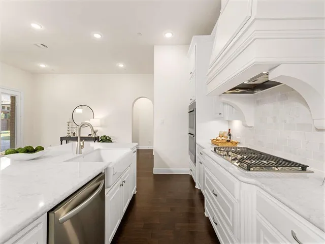a kitchen with white cabinets and sink