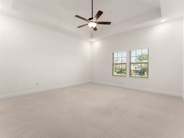 an empty room with windows and ceiling fan