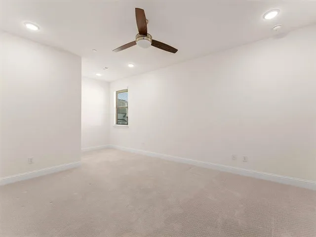 an empty room with a ceiling fan and window