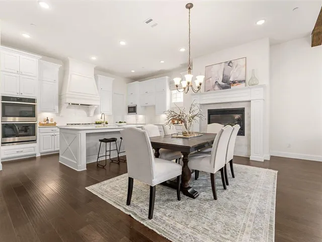 a dining room with stainless steel appliances kitchen island a table chairs and a kitchen view