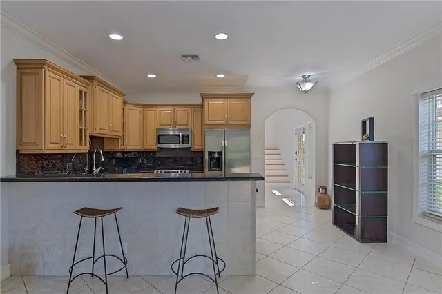 a view of a kitchen with kitchen island granite countertop wooden cabinets and stainless steel appliances
