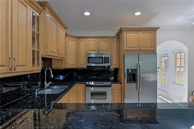 a kitchen with stainless steel appliances granite countertop a refrigerator a stove and a sink