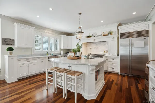 a kitchen with stainless steel appliances a refrigerator a stove a sink dishwasher and white cabinets with wooden floor