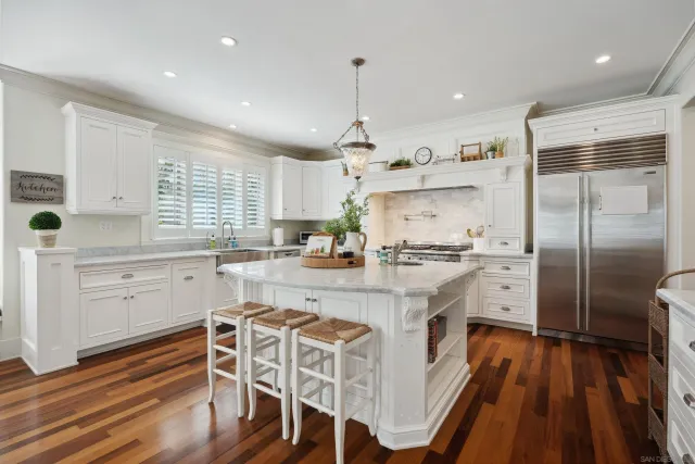 a kitchen with stainless steel appliances a refrigerator a stove a sink dishwasher and white cabinets with wooden floor