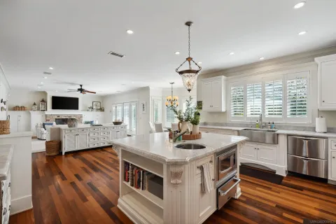 a kitchen with stainless steel appliances a stove a sink dishwasher a oven with white cabinets and wooden floor