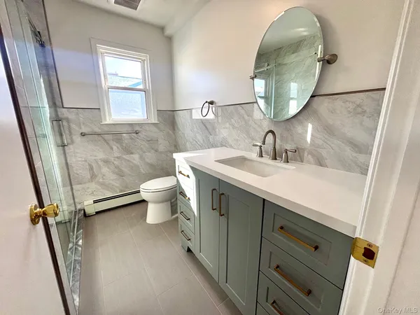 a bathroom with a sink mirror toilet and next to a window