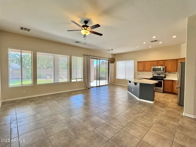 a view of an empty room with kitchen and window