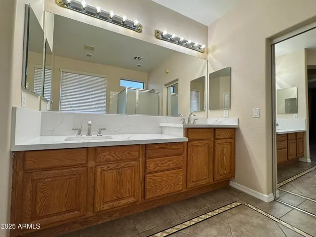 a spacious bathroom with a double vanity sink a mirror and a shower