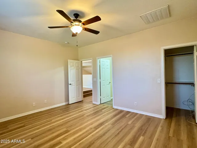 an empty room with a ceiling fan and wooden floor