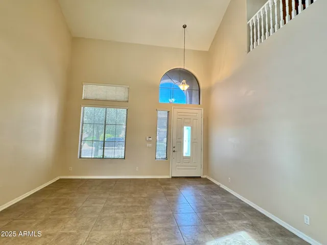 an empty room with chandelier fan and windows