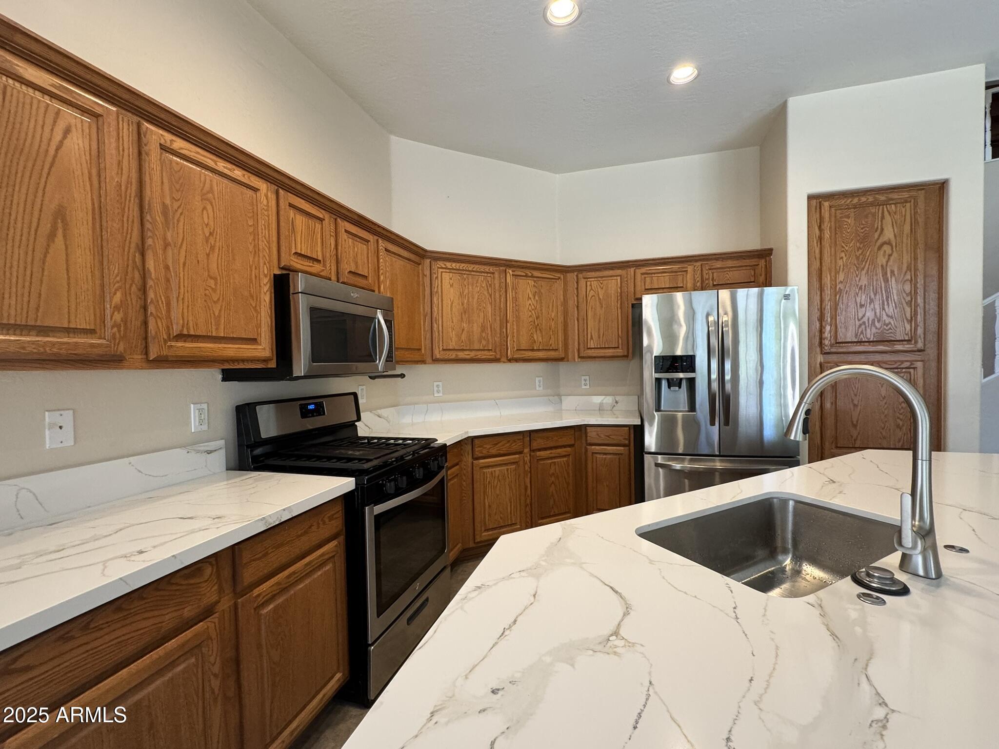 2671 South Dragoon Drive Chandler, AZ 85286 - Photo 8 of 41 a kitchen with stainless steel appliances wooden cabinets a sink and a stove