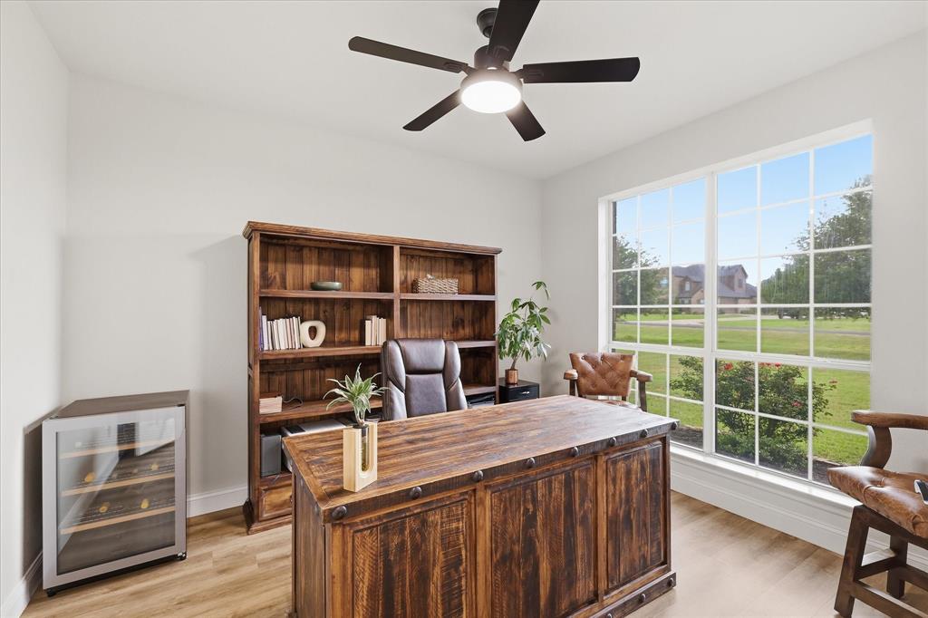 430 Ridgecrest Place Sanger, TX 76266 - Photo 5 of 40 Light wood-finish flooring complements the bright white walls of this space, featuring a large multi-pane window, a ceiling fan with integrated lighting, and built-in shelving