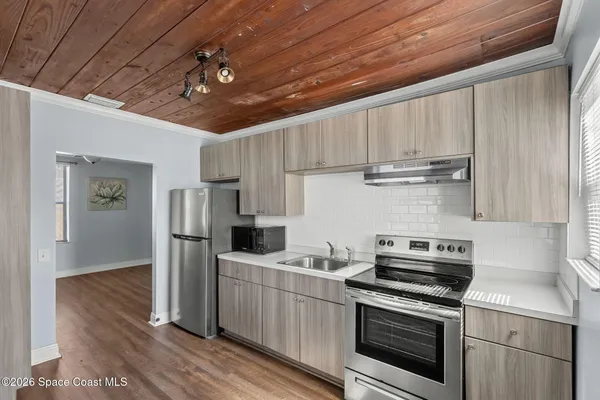 a kitchen with stainless steel appliances a stove a sink dishwasher a refrigerator and cabinets with wooden floor
