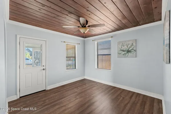 an empty room with wooden floor chandelier fan and windows