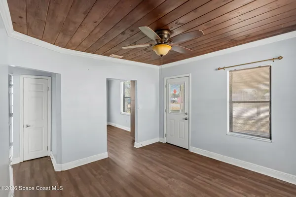 an empty room with wooden floor chandelier fan and windows