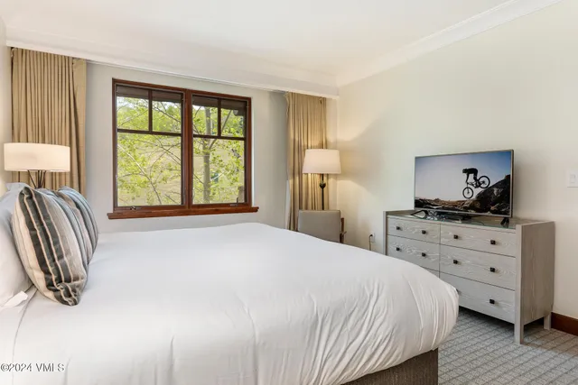 a bedroom with a bed and a dresser next to a window