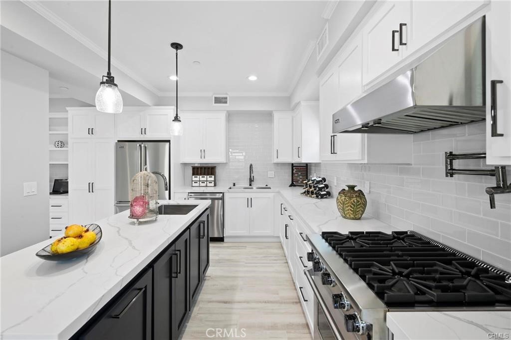112 Van Nuys Avenue Oxnard, CA 93035 - Photo 15 of 58 a kitchen with stainless steel appliances a stove a sink a refrigerator wooden floor and white cabinets