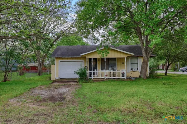 a front view of a house with a garden and trees